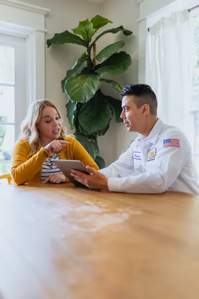 Mister Sparky tech is speaking with a homeowner at her kitchen table at a home in Melbourne FL
