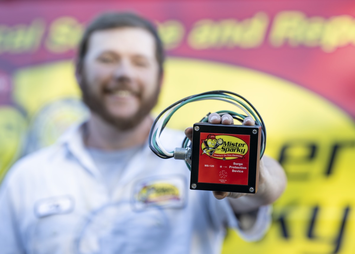 Mister Sparky holding whole home surge protector with proper joules rating 